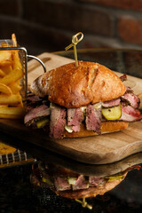 Pastrami sandwich on rye bread served with pickles and mustard sauce. Tasty sandwich with french...
