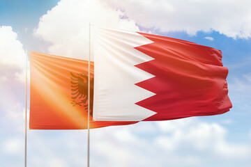 Sunny blue sky and flags of bahrain and albania