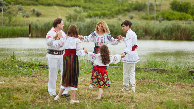 Full length photo of a happy family with kids in traditional romanian clothes in a countryside.