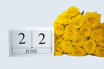 Wooden, white calendar June 22 , bouquet of yellow roses lie next to it . The concept of holidays, important date, event . High quality photo