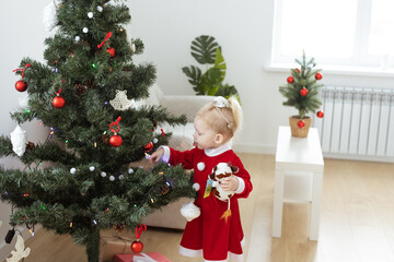 Obraz na płótnie Canvas Toddler child with cochlear implant decorating christmas tree - deafness and diversity and innovating medical technologies for hearing aid
