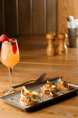 baked bruschetta with salmon, cheese, sun-dried tomatoes and avocado in gray plate on bright background