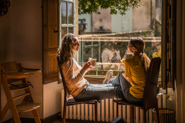 Cheerful teen girl spending time with her parent while drinking tea