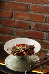 Salad with veal and tomatoes. Beef steak with raw vegetables mix side view. Grilled meat with garnish close-up. Delicious main course on table