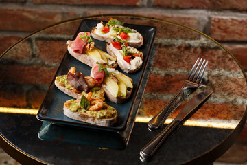 Bruschettas with vegetables. Start dishes with cherry tomatoes, avocado, cream cheese and shrimps. Food composition, tasty italian meal