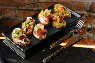 Bruschettas with vegetables. Start dishes with cherry tomatoes, avocado, cream cheese and shrimps. Food composition, tasty italian meal