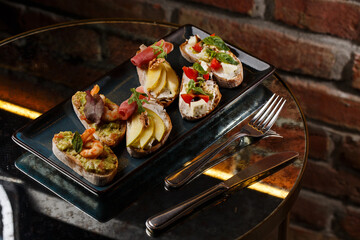 Bruschettas with vegetables. Start dishes with cherry tomatoes, avocado, cream cheese and shrimps. Food composition, tasty italian meal