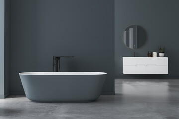 Modern minimalist bathroom interior, modern bathroom cabinet, white sink, oval mirror, concrete flooring, bathroom accessories, bathtub, dark blue walls. 3d rendering
