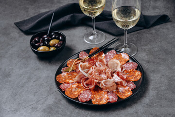 Different types of salami on a black platter, an appetizer for white wine or Prosecco in a restaurant aperitif meal