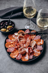 Different types of salami on a black platter, an appetizer for white wine or Prosecco in a restaurant aperitif meal