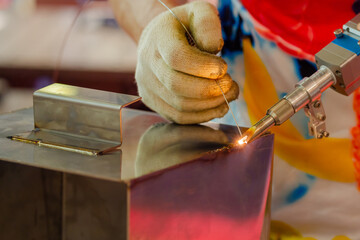 Welder hands using portable handheld laser welding machine - close up. Manufacturing, industrial,...