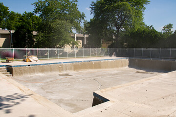 Jack hammer nearby swimming pool ladder in front of tiles removed wall after demolition for...