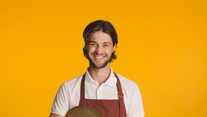 Young friendly waiter looking at camera sincerely smiling against a colorful background. Attractive...