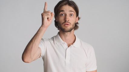 Inspired man raising fore finger getting some good idea over white background. Pensive guy remember...