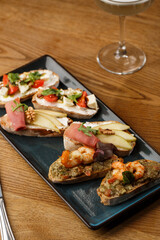 Bruschettas with vegetables. Start dishes with cherry tomatoes, avocado, cream cheese and shrimps. Food composition, tasty italian meal