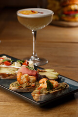 Bruschettas with vegetables. Start dishes with cherry tomatoes, avocado, cream cheese and shrimps. Food composition, tasty italian meal