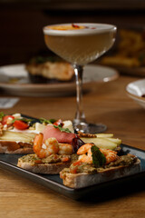 Bruschettas with vegetables. Start dishes with cherry tomatoes, avocado, cream cheese and shrimps. Food composition, tasty italian meal