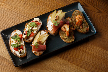 Bruschettas with vegetables. Start dishes with cherry tomatoes, avocado, cream cheese and shrimps. Food composition, tasty italian meal
