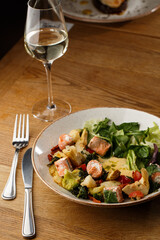 A salad with grilled salmon, mashed avocado and lettuce dressed with cream cheese. Close-up of the dish in a brown bowl isolated on brown background.