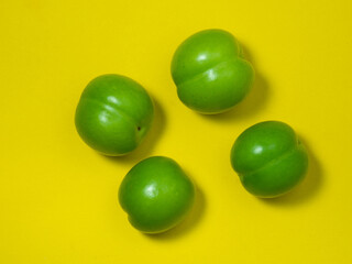 Cherry plum fruits on a yellow background. Healthy green fruit. Southern fruit isolate.