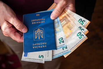 a woman pensioner holds in her hands a Ukrainian biometric passport with Poland zloty banknotes - obrazy, fototapety, plakaty
