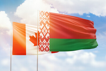Sunny blue sky and flags of belarus and canada
