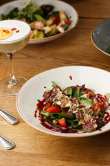 Salad with veal and tomatoes. Beef steak with raw vegetables mix side view. Grilled meat with garnish close-up. Delicious main course on table