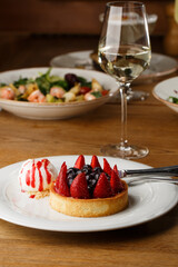 Berry tartlets with curd cream on a wooden background. Summer fruit baking. Tartlets with raspberries, blueberries and red currants. Served with ice cream.
