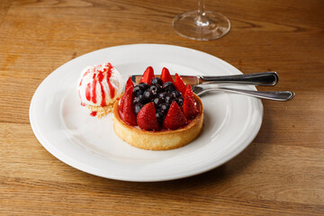 Berry tartlets with curd cream on a wooden background. Summer fruit baking. Tartlets with raspberries, blueberries and red currants. Served with ice cream.