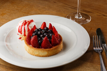 Berry tartlets with curd cream on a wooden background. Summer fruit baking. Tartlets with raspberries, blueberries and red currants. Served with ice cream.