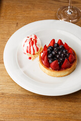 Berry tartlets with curd cream on a wooden background. Summer fruit baking. Tartlets with raspberries, blueberries and red currants. Served with ice cream.