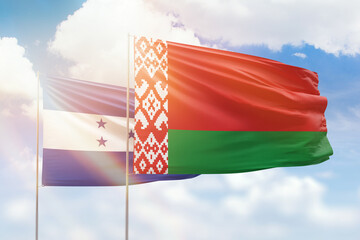 Sunny blue sky and flags of belarus and honduras