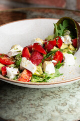 Tasty and healthy salad with arugula, brie cheese, avocado, cherry tomatoes and strawberry. Top view. The flat lay. Banner