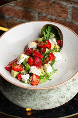 Tasty and healthy salad with arugula, brie cheese, avocado, cherry tomatoes and strawberry. Top view. The flat lay. Banner