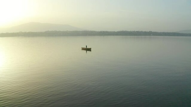 Aerial Shot Of A Man Alone On A Boat In The Middle Of Lake Geneva, At Sunrise, In Switzerland