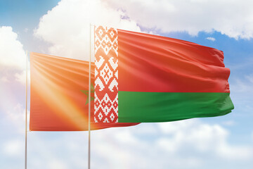 Sunny blue sky and flags of belarus and morocco