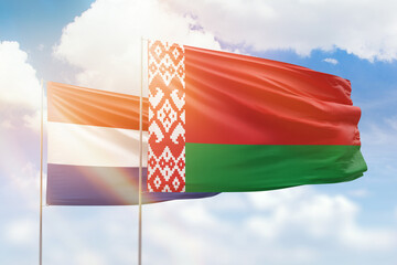 Sunny blue sky and flags of belarus and netherlands