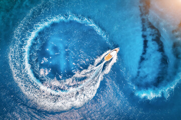 Aerial view of the speed boat in clear blue water at sunset in summer. Top view from drone of fast...