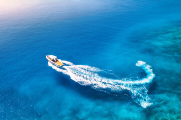 Aerial view of the speed boat in clear blue water at sunset in summer. Top view from drone of fast...