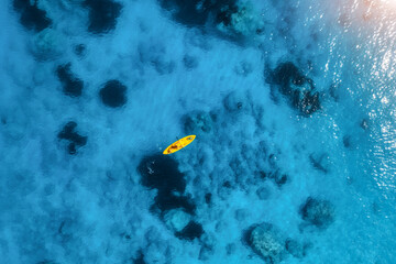 Aerial view of yellow kayak in blue sea at sunset in summer. Man on floating canoe in clear azure...