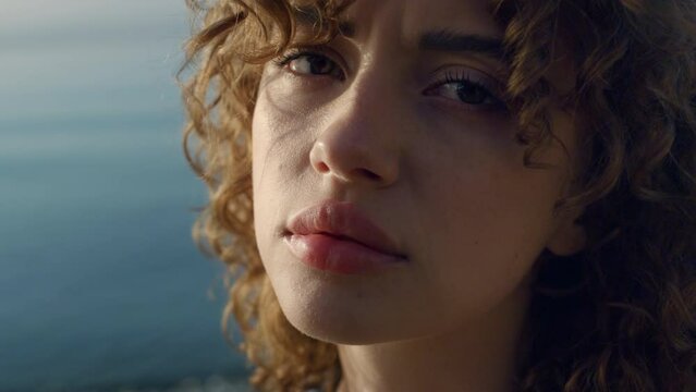 Sad woman posing at camera on beach. Closeup depressed girl blinking eyes