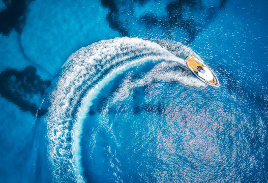 Aerial view of the speed boat in clear blue water at sunset in summer. Top view from drone of fast floating yacht in mediterranean sea. Travel in Oludeniz, Turkey. Tropical landscape with motorboat
