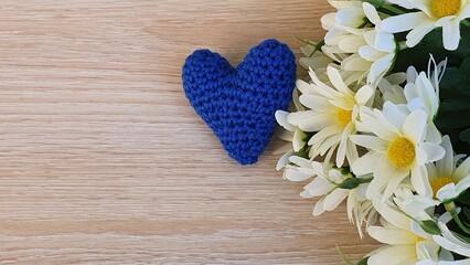 Obraz na płótnie Canvas Flowers and a crochet heart on wooden background.