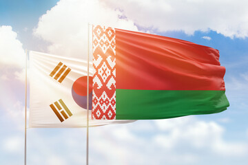 Sunny blue sky and flags of belarus and south korea