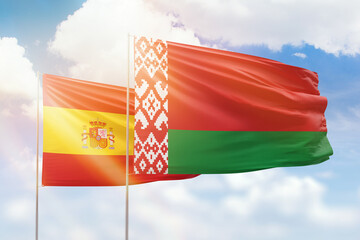 Sunny blue sky and flags of belarus and spain