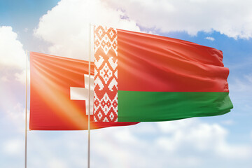 Sunny blue sky and flags of belarus and switzerland