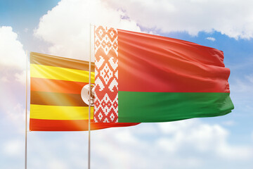 Sunny blue sky and flags of belarus and uganda