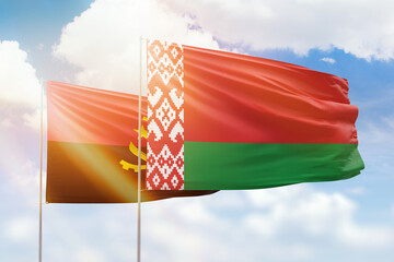 Sunny blue sky and flags of belarus and angola