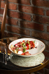 Prosciutto crudo ham salad with mozzarella cheese and arugula on a plate. Bright background. Top view. Copy space