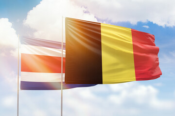 Sunny blue sky and flags of belgium and costa rica